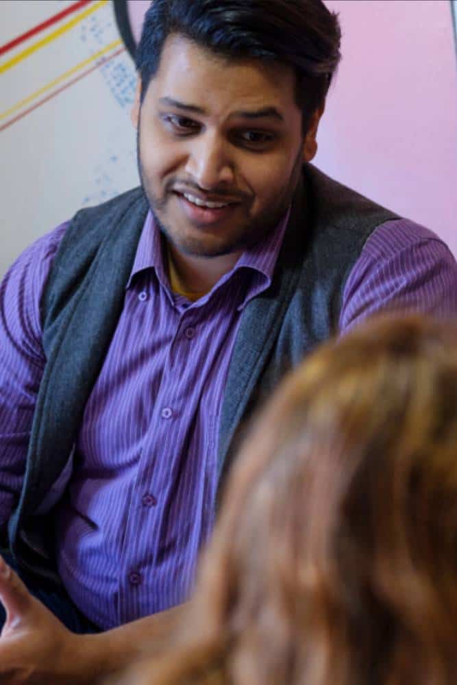 Man in discussion wearing purple shirt and grey vest