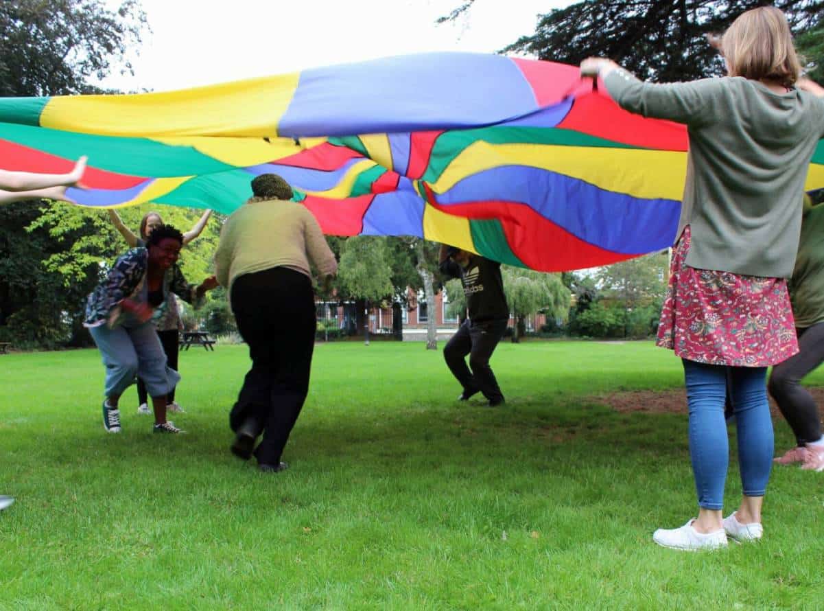 People playing with colorful parachute in park