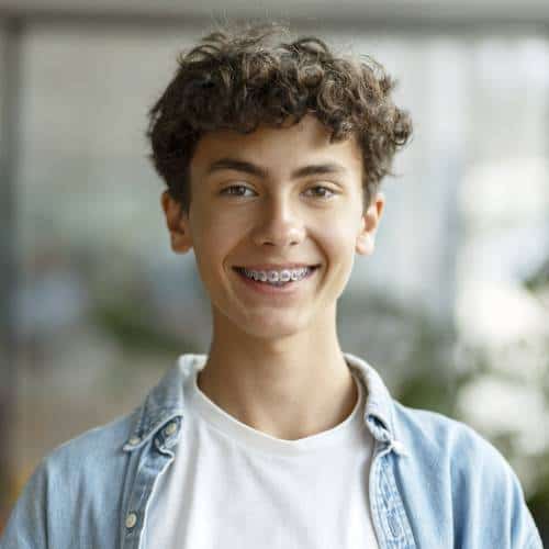Smiling teen boy with braces wearing a denim jacket.