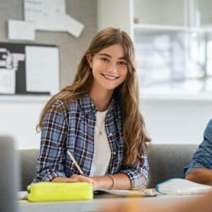 Smiling student with notebook in classroom setting.