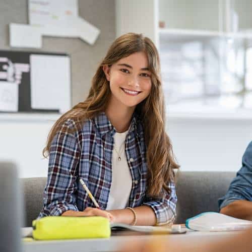 Smiling student with notebook in classroom setting.
