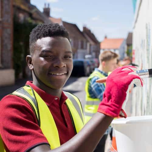 Young volunteer painting a wall outdoors.